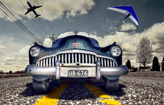 A car on holiday with a plane and a para-glider in the background.