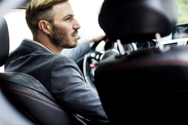 Young man driving a car in grey suit