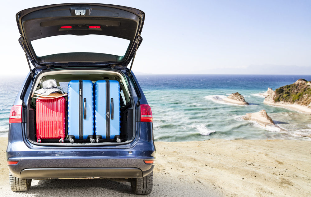 Car parked on beach with boot open and suitcases inside